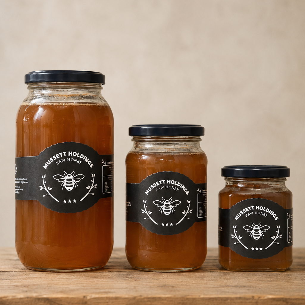 Three jars of honey with labels on a wooden surface and beige background
